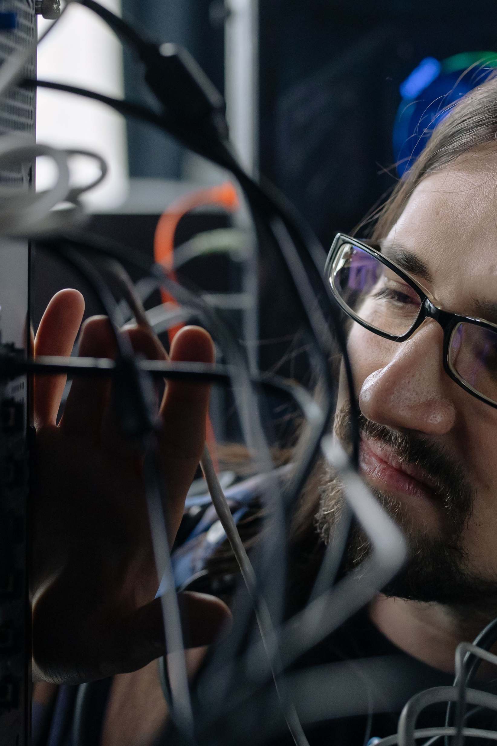 Server racks and network cabling in a data hall — IT specialist handling network cables in a server room