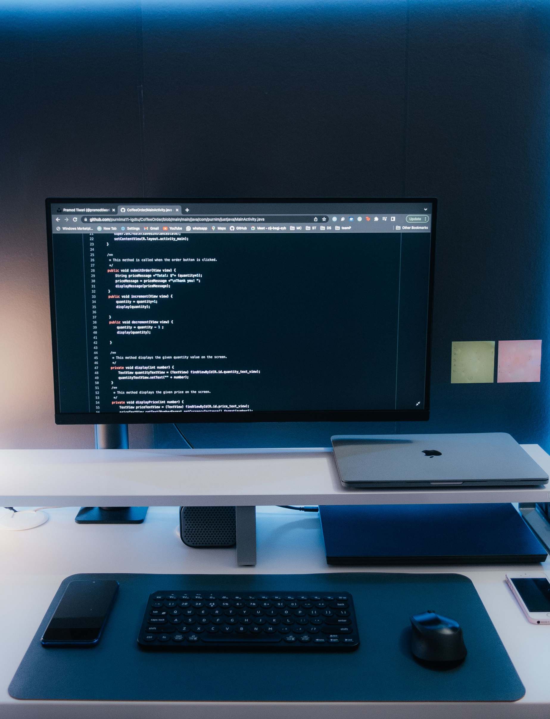 Overhead view of a developer workspace with laptop — minimalist home office desk setup with coding on a large monitor
